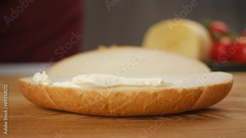 Close up of unrecognizable young woman spreading soft butter on slice of bread. Spreading cream cheese on bread. Housewife making sandwich for breakfast. Food concept photo