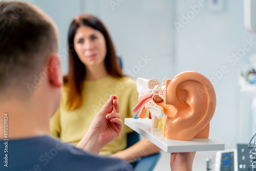 an ENT doctor consults a patient in the clinic's office tells about the possible consequences of the operation shows of ear and nasal canals photo