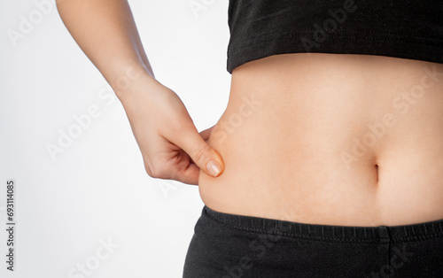 Girl pulls the skin on the abdomen, showing the body fat. Treatment and disposal of excess weight, the deposition of subcutaneous fat.