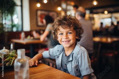 Smiling Young Boy Enjoying a Meal in a Busy Restaurant
