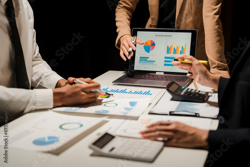 Group of confident business people point to graphs and charts to analyze market data, balance sheet, account, net profit to plan new sales strategies to increase production capacity. photo
