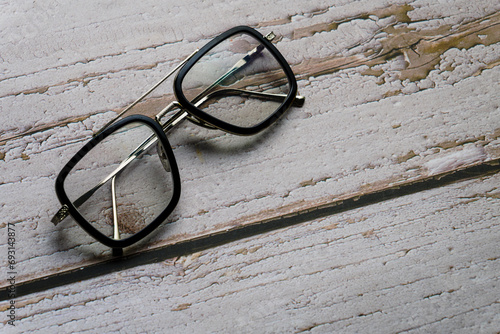 Photochromic lens eye glasses on wooden background flat lay