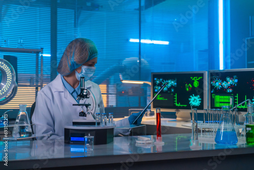 Female scientist sitting in a research lab with test tubes and flasks. A female doctor in a white coat examining research data in a folder. photo