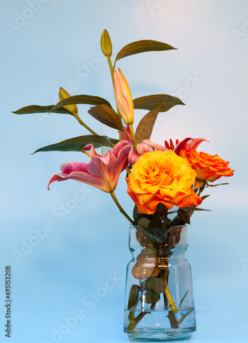 lirios morados y rosas amarillas naranjas en fondo celeste 