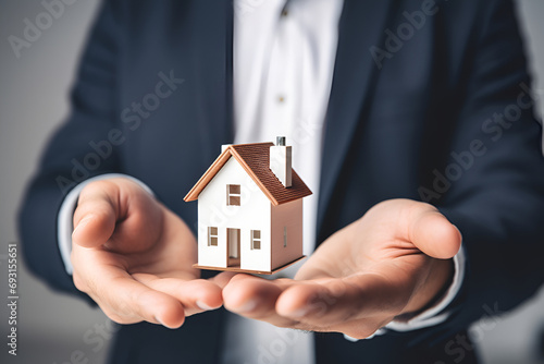 A man holds a model of a house in his hands
