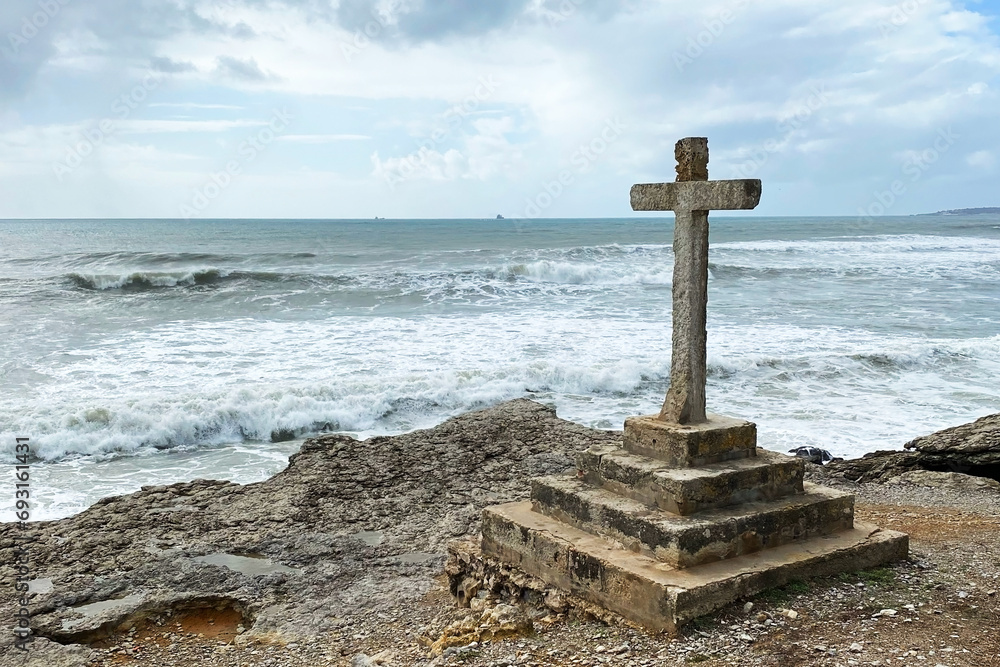 Stone cross on the coast of the Atlantic ocean in Tarragona, Spain Stone cross on the coast of the Atlantic ocean in Tarragona, Spain