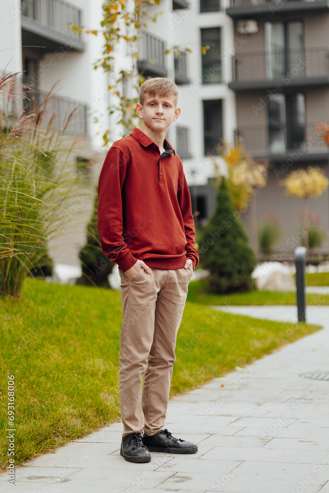 Vertical close-up portrait of a teenager in casual clothes. Happy smiling teenager in autumn park in sunlight. A beautiful child looks at the camera in nature. Vertical close-up portrait of a teenager in casual clothes. Happy smiling teenager in autumn park in sunlight. A beautiful child looks at the camera in nature.