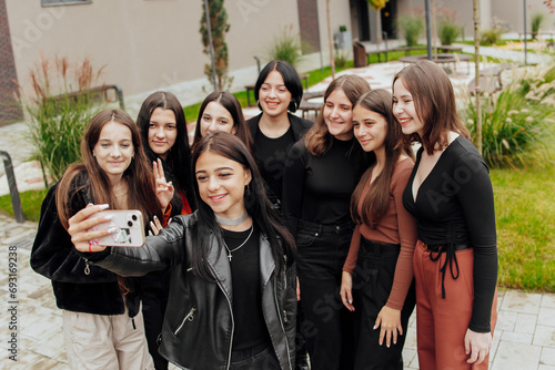 Friends taking a big group selfie smiling at the camera - laughing young people standing outdoors and having fun - portrait of cheerful schoolchildren outside school - human resources concept