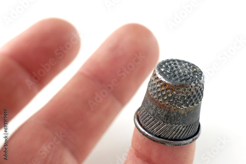 Fingers of a seamstress with a thimble on a white background