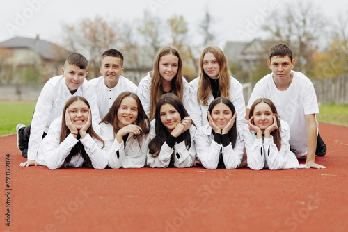 A group of many happy teenagers dressed in the same outfit having fun and posing in a stadium near a college. Concept of friendship, moments of happiness. School friendship photo