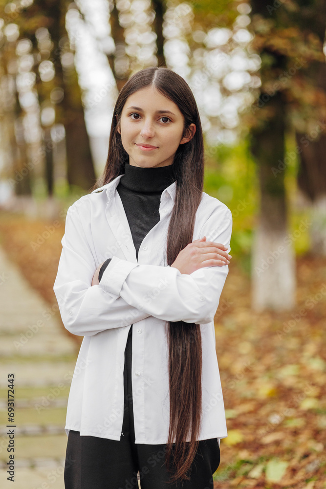 Vertical photo. Beautiful carefree young teenage girl in casual clothes. Portrait of a beautiful girl against the background of nature with a blurred background. Vertical photo. Beautiful carefree young teenage girl in casual clothes. Portrait of a beautiful girl against the background of nature with a blurred background.