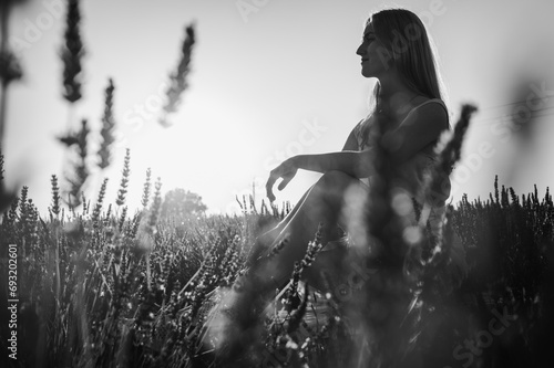 black and white photo  in the rays of the setting sun  portrait of a relaxed young girl in a white dress  sitting on a white bench  in thought  breathing fresh air  sitting in a lavender field
