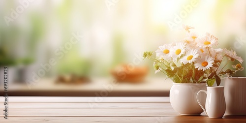 Blurred background with focus on wooden kitchen table top and breakfast tableware, along with a vase of garden flowers. Space for text.