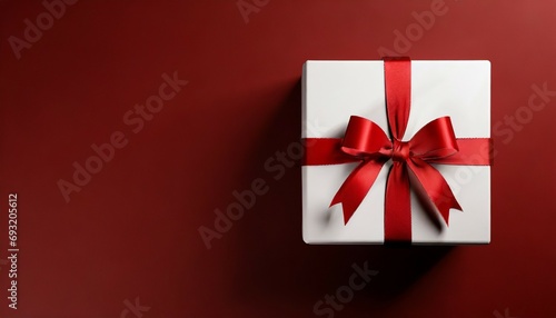 white gift box or top view of white present box tied with red ribbon bow on dark red background with empty space on the left side minimal conceptual 3d rendering