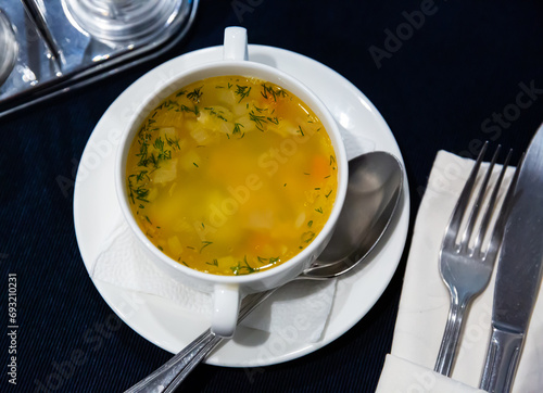 White ceramic tureen with thick vegetable soup cooked in chicken broth photo