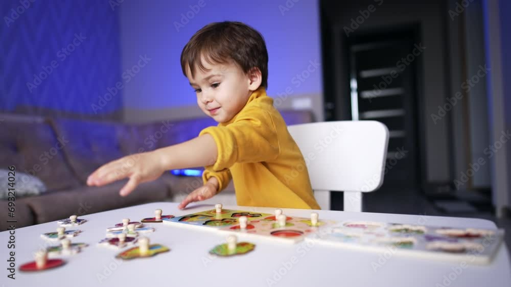 Baby boy in yellow sweater reaches for a puzzle piece. Toddler kid playing with puzzles at home. Baby boy in yellow sweater reaches for a puzzle piece. Toddler kid playing with puzzles at home.
