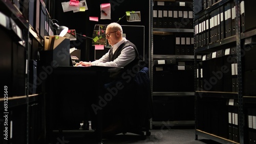 Private detective reading files, checking forensic evidence reports on classified documents in incident room. Law officer undertaking investigatory services with witness statements, uncover clues. photo