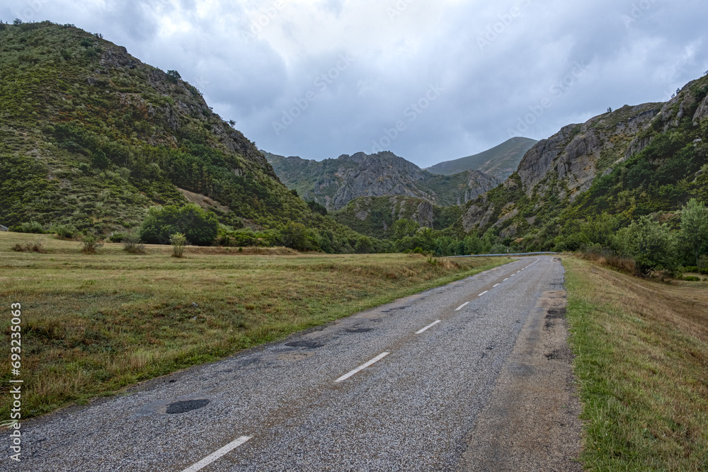 Beautiful landscape photo of road going through natural park full of mountains and trees during summer in cordillera Cantabrica, picos da europa, leon, asturias, spain