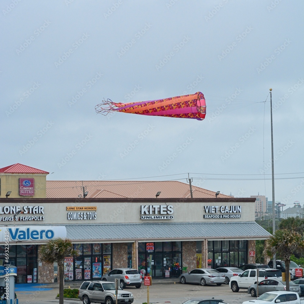 High flying kite tethered above strip mall along Galveston seawall