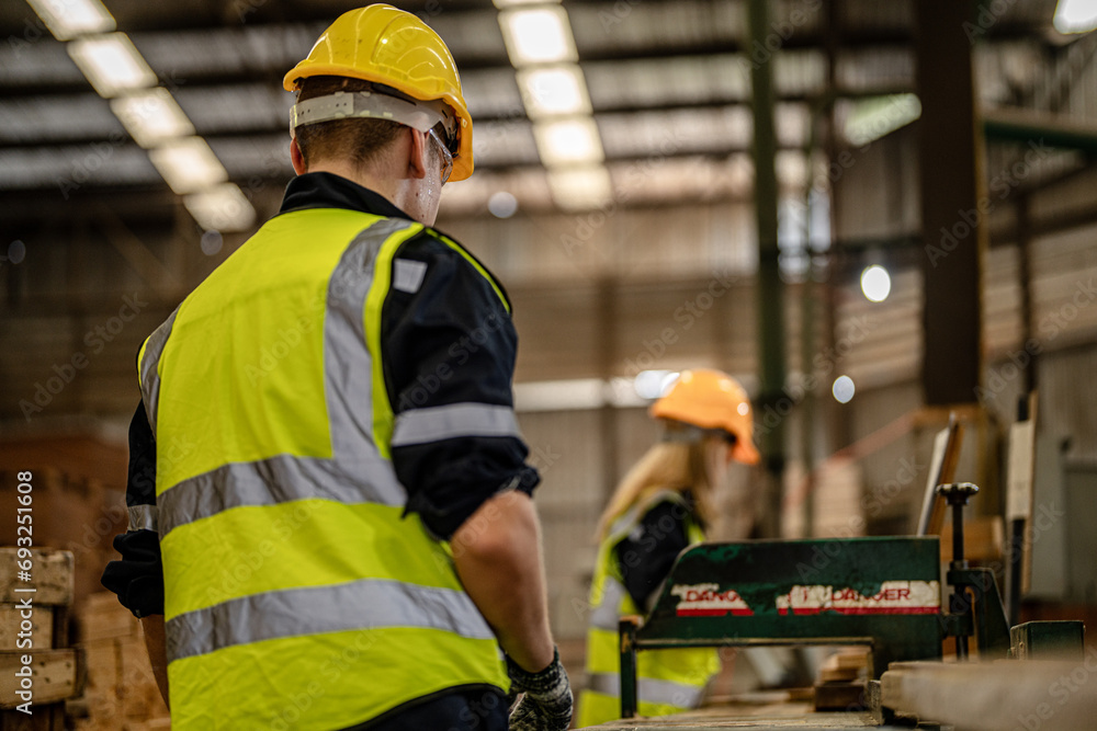 man cleaning timber wood in dark warehouse industry. Team worker carpenter wearing safety uniform and hard hat working and checking the quality of wooden products at workshop manufacturing. man cleaning timber wood in dark warehouse industry. Team worker carpenter wearing safety uniform and hard hat working and checking the quality of wooden products at workshop manufacturing.
