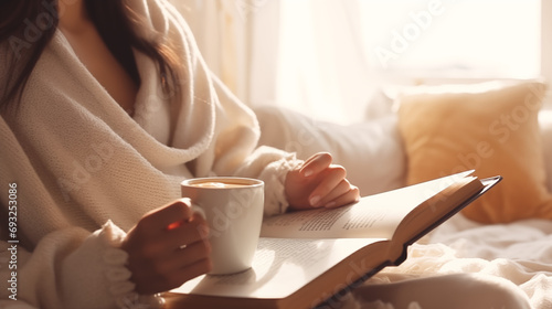 close up of woman reading a book drinking coffee at window in winter photo