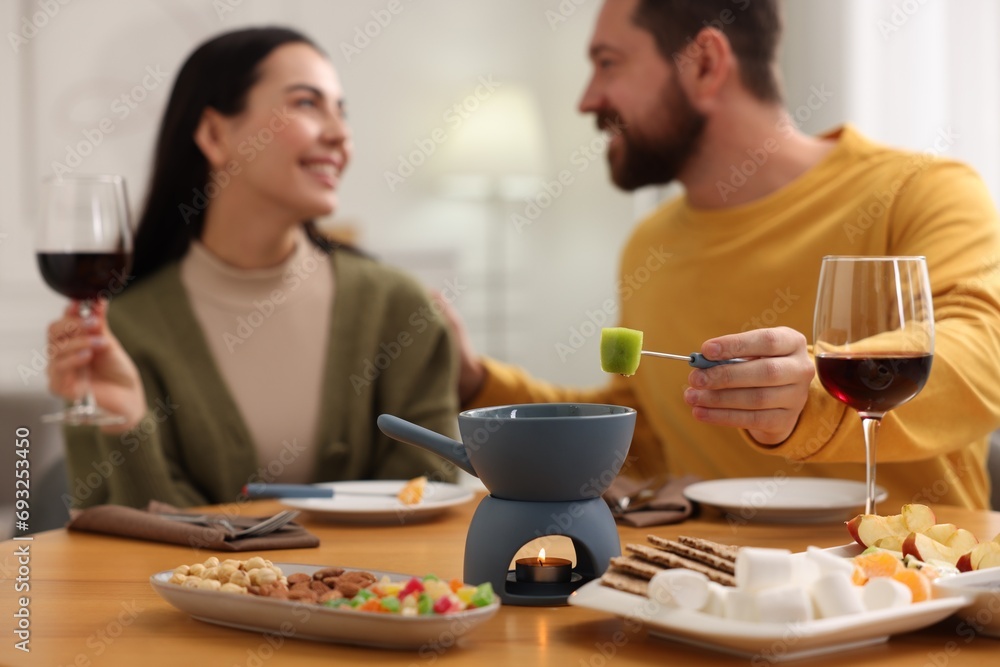 Affectionate couple enjoying fondue during romantic date indoors, selective focus