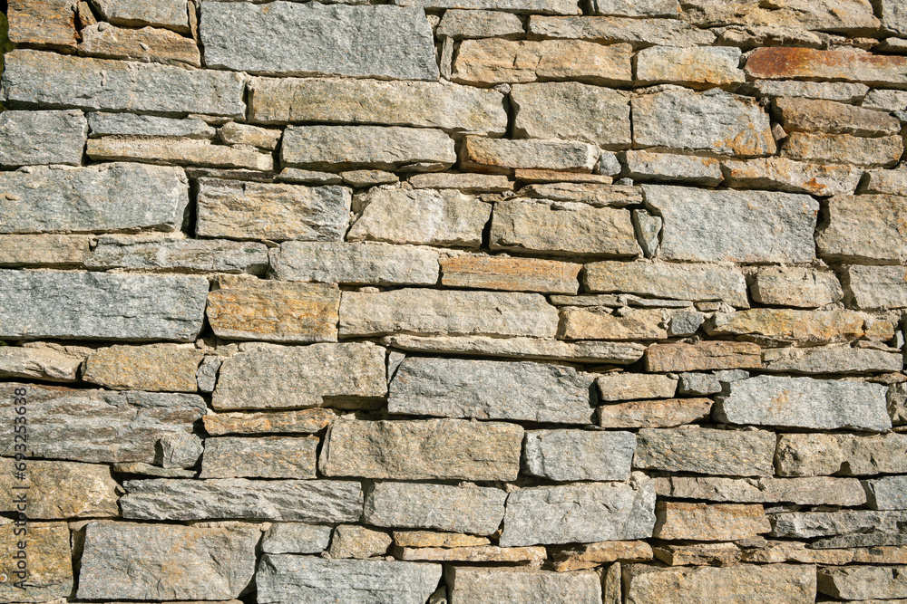 texture of a stone wall with rugged and wrinkled surface, characterized by a variety of earthy tones and intriguing details, offering an atmosphere of authenticity and solidity.
