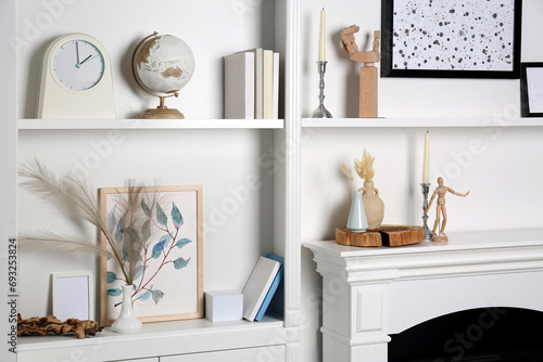 White shelves with books, globe and different decor indoors. Interior design photo