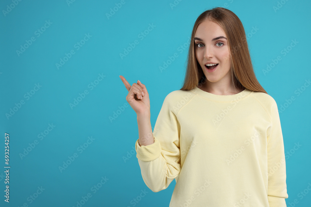 Special promotion. Emotional woman pointing at something on light blue background, space for text Special promotion. Emotional woman pointing at something on light blue background, space for text