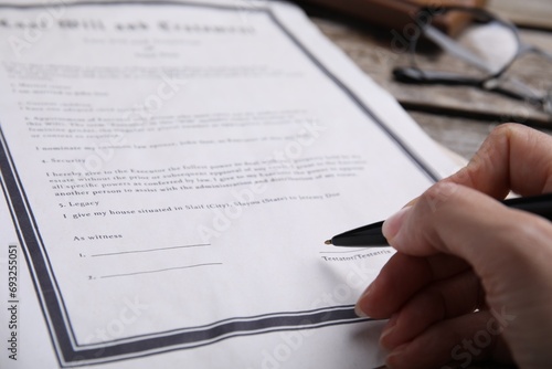 Woman signing last will and testament at table, closeup photo