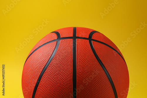 One new basketball ball on yellow background, closeup