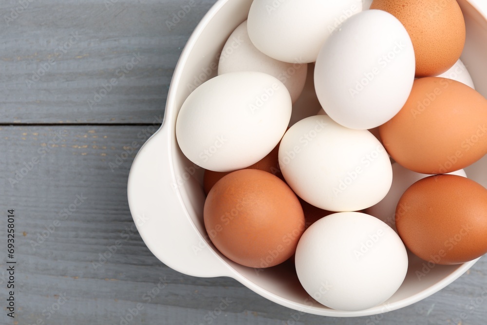 Unpeeled boiled eggs in saucepan on grey wooden table, top view. Space for text Unpeeled boiled eggs in saucepan on grey wooden table, top view. Space for text