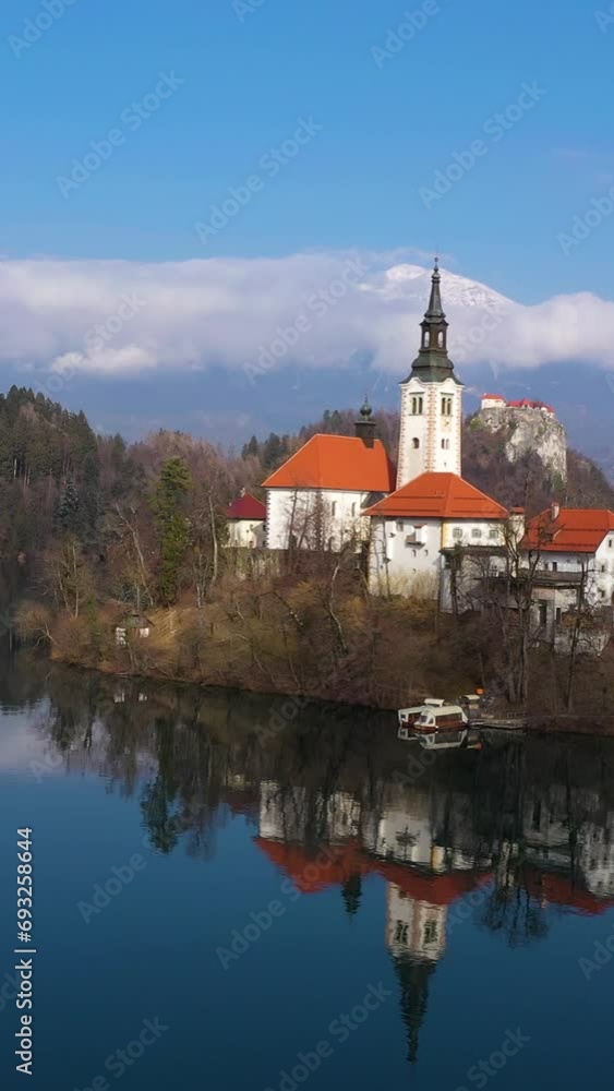 Bled Lake, Marijinega Vnebovzetja Church and Blejski Castle. Julian Alps and Reflection in the Lake. Slovenia. Aerial View. Drone Flies Backwards and Upwards. Vertical Video Bled Lake, Marijinega Vnebovzetja Church and Blejski Castle. Julian Alps and Reflection in the Lake. Slovenia. Aerial View. Drone Flies Backwards and Upwards. Vertical Video