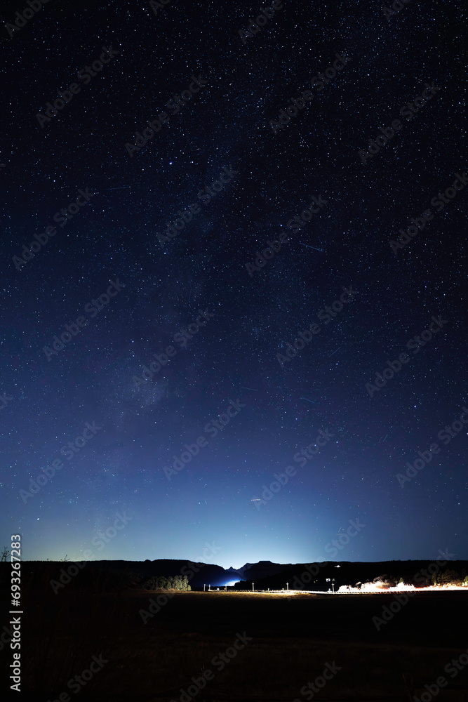 Fototapeta premium headlights streak under blue starry sky