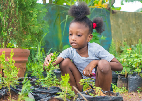 A young female African Nigerian teenager girl child or florist, playing in an Horticulture garden filled with colorful green flowers in Nigeria