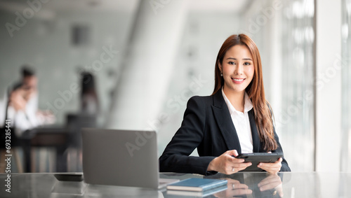 Portrait of confident businesswoman with colleagues in boardroom. Using digital tablet during a meeting.