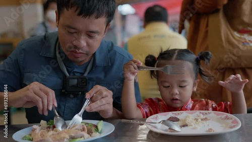 Dad with little daughter eat chicken rice in Yaowarat street food Bangkok Thailand