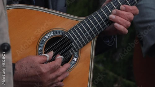 Strumming a Portuguese guitar outdoors. Close up