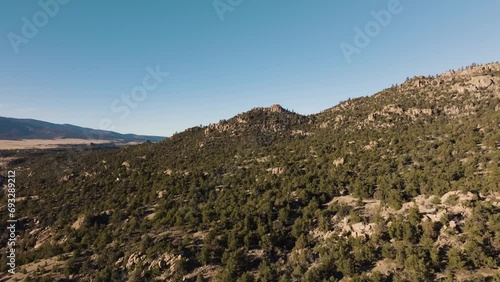 Drone flying over Midland Hill in Colorado with mountains in the background and trees in foreground photo