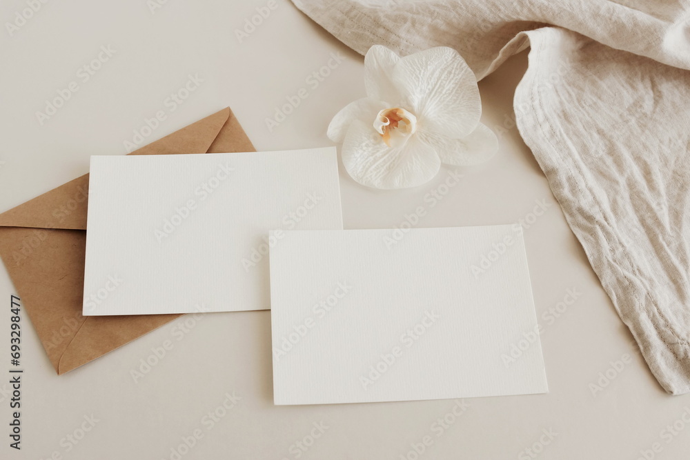 Greeting Cards mockup, empty white blanks, envelopes and orchid flower top view on beige background with copy space. flat lay. Empty white Blank, greeting card template, invitation. Greeting Cards mockup, empty white blanks, envelopes and orchid flower top view on beige background with copy space. flat lay. Empty white Blank, greeting card template, invitation.