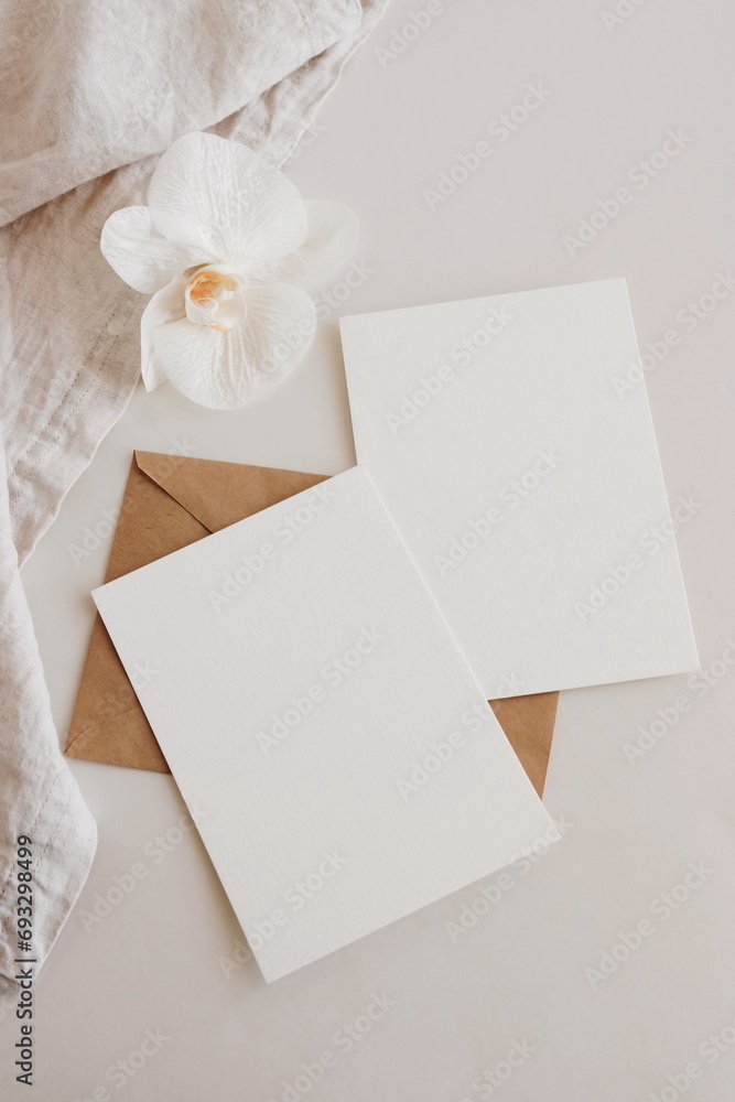 Greeting Cards mockup, empty white blanks, envelopes and orchid flower top view on beige background with copy space. flat lay. Empty white Blank, greeting card template, invitation. Greeting Cards mockup, empty white blanks, envelopes and orchid flower top view on beige background with copy space. flat lay. Empty white Blank, greeting card template, invitation.