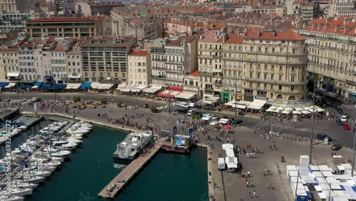 Tourists and visitors walking on the busy streets along the old port of Marseille in France on a hot summer morning.