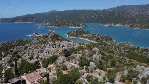 Aerial tour over Aperlai Ancient City with mountains, blue waters and boats sailing in Turkey photo