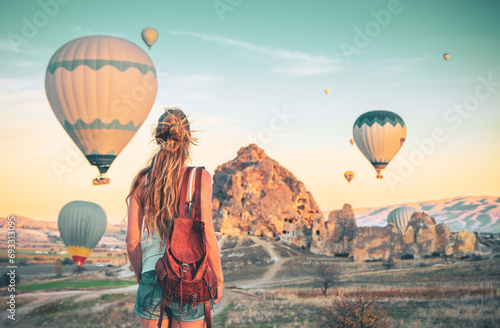 Young female tourist looking colorful hot air balloon flying over Cappadocia landscape- Travel, vacation, tour tourism in Turkey