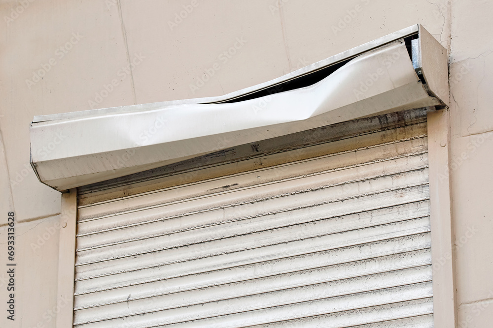 Damaged rolling shutter, window with closed roller shutters. House facade with damaged roller shutter on first floor, security and protection concept