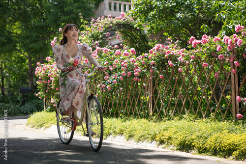 Young and beautiful women ride bicycles in the courtyard full of flowers photo
