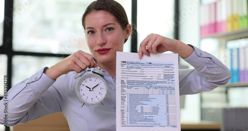 Agent holding Form 1040 Income Tax Return and alarm clock photo