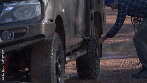 Man puts on a tyre valve stem cap before exiting frame. photo