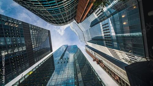 Time lapse Low angle of tall corporate buildings skyscraper with reflection of clouds among high buildings and glass elevator in building center photo