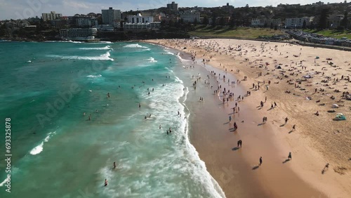 Aerial view Footage of Crowd people visiting and relaxing at iconic Bondi Beach with sunshine during the summer weekends in Sydney photo